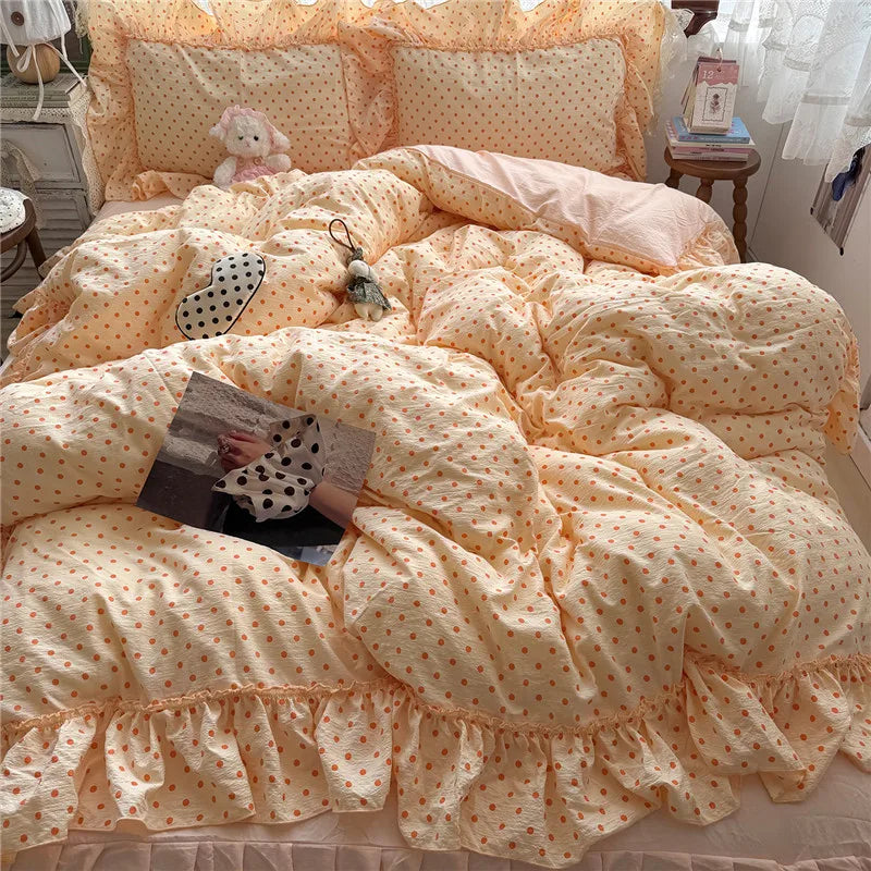 A cozy bed made with a pale peach and white polka-dot bedding set, including a comforter, matching pillowcases, and ruffled trim, styled in a bedroom setting with decorative pillows and accessories.