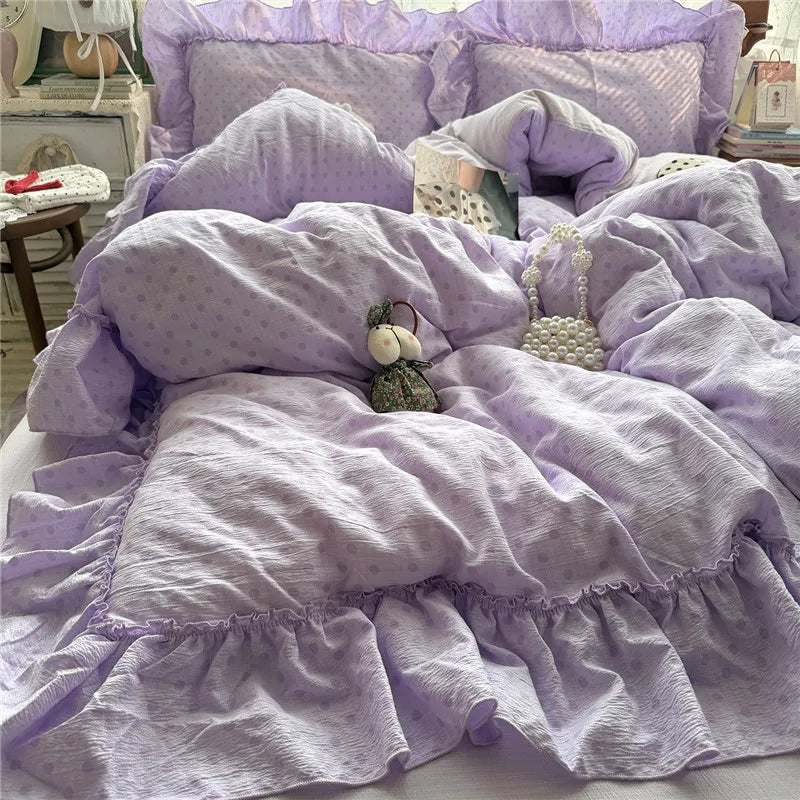 A lavender bedding set styled on a bed, featuring a textured crinkle fabric duvet cover with ruffled edges, matching pillowcases, and coordinating decorative accessories.
