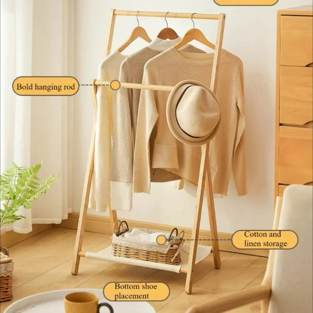 A wooden A-frame clothing rack with three beige sweaters and a hat hanging on it, shown in a styled room with callout labels pointing to the hanging rod, cotton and linen storage shelf, and bottom shoe placement.
