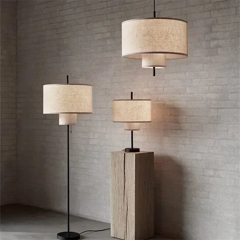 Three lamps of different heights against a brick wall.