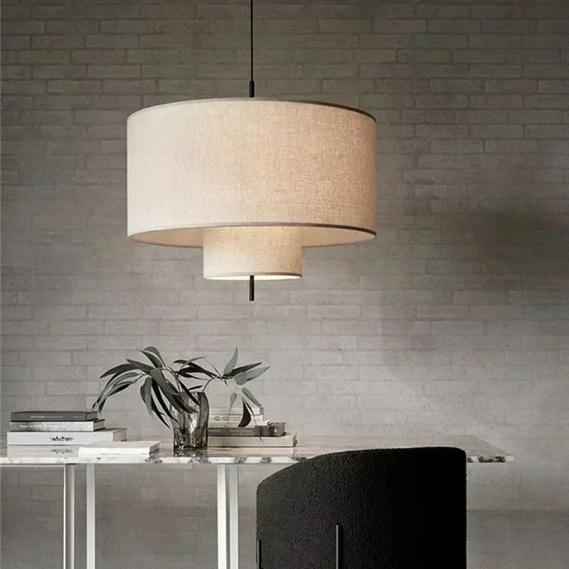 Modern pendant light hanging above a table with decorative items against a brick wall.