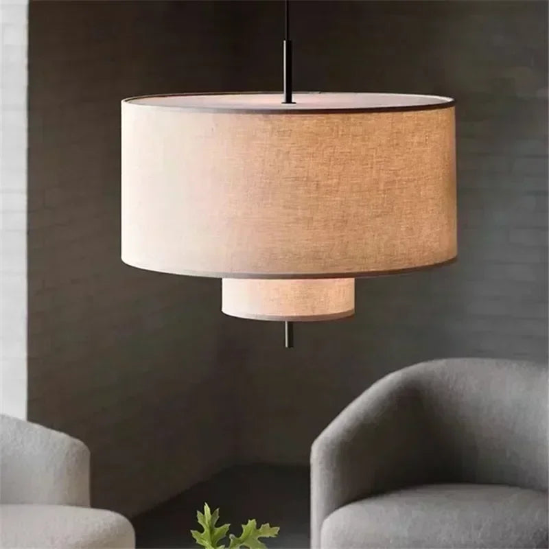 Pendant light fixture with a textured shade in a room with gray chairs and a plant.