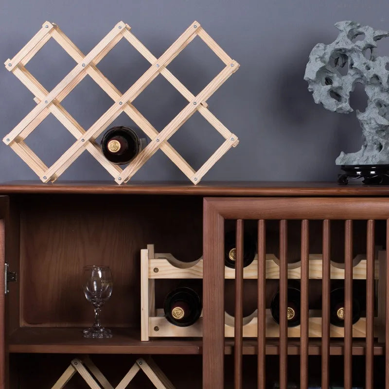 Wooden wine rack on a wooden cabinet with wine bottles and a glass.